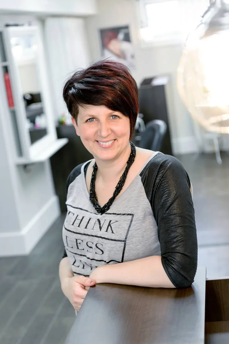 Nancy, owner of C-Cybo Coiffure, leaning on her salon's front desk