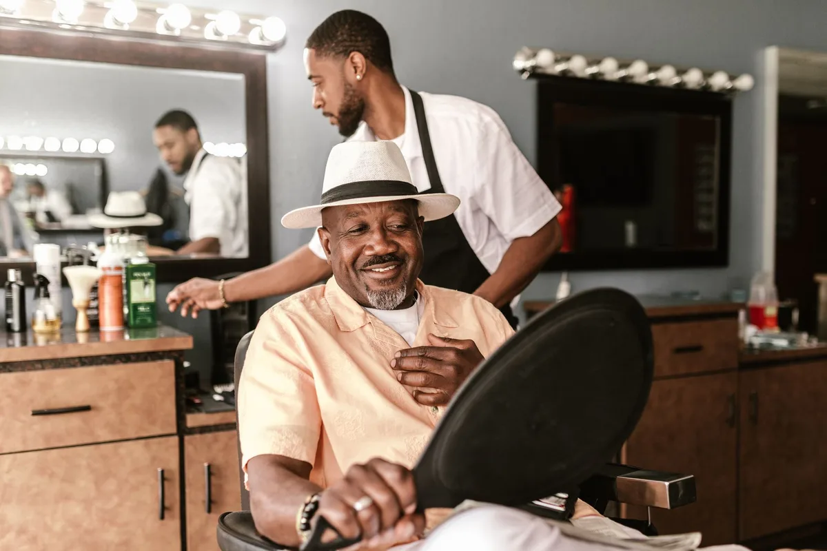 Satisfied client looking at himself in the mirror at the end of his barbershop cut