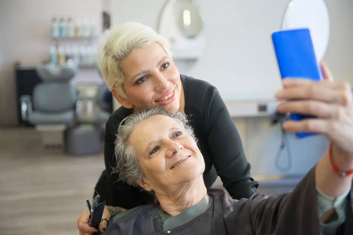 Hairstylist and client taking the phone photo that will become the salon's Instagram post