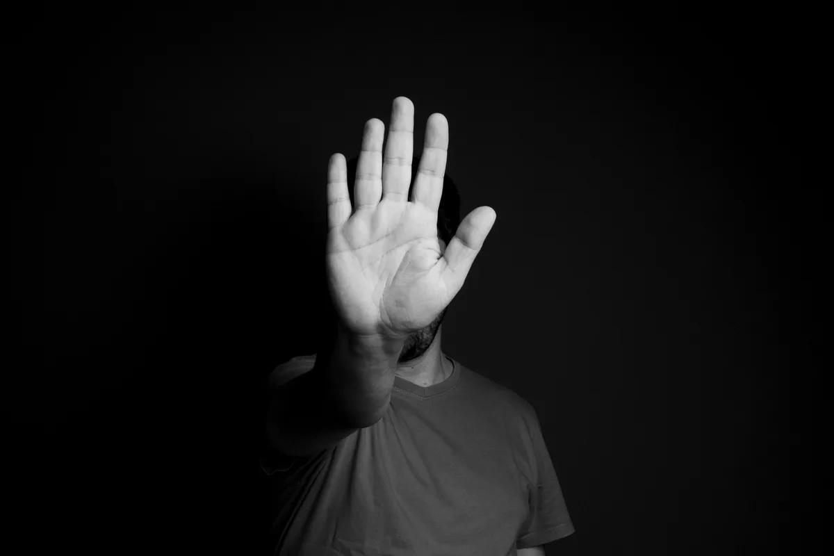 Main ouverte levée en signe de refus, en noir et blanc, comme un salon qui refuse de brader ses prix pour faire revenir un client